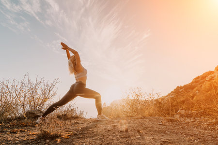 Woman Stretching on Mountain Ridge at Sunsetの写真素材