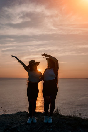 Silhouettes of Two Women Against a Sunset Skyの写真素材