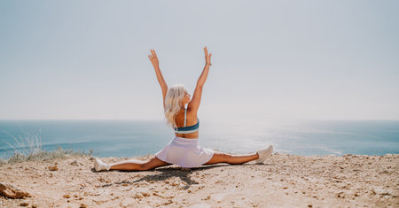 Woman Doing Splits on a Cliff Overlooking the Seaの写真素材