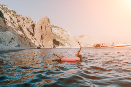Woman, floating, vacation. Woman enjoying summer leisure on an inflatable ring in clear blue sea.の写真素材