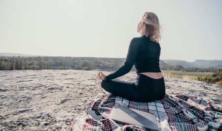 Woman Meditating on a Clifftop with a Laptop and Phoneの写真素材