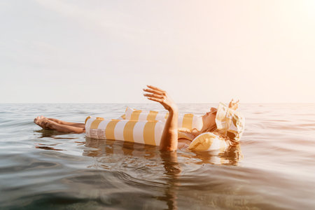 Woman Float Relaxing Beach Ocean Summer - A woman in a striped inflatable float is relaxing in the ocean on a sunny day.の写真素材