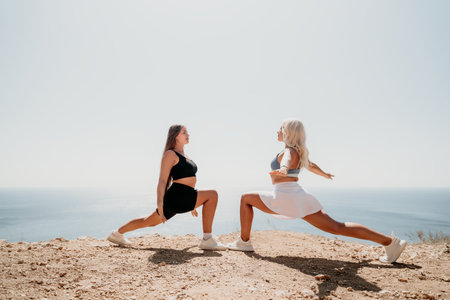 Two Women Stretching on a Cliffside with Ocean Viewの写真素材