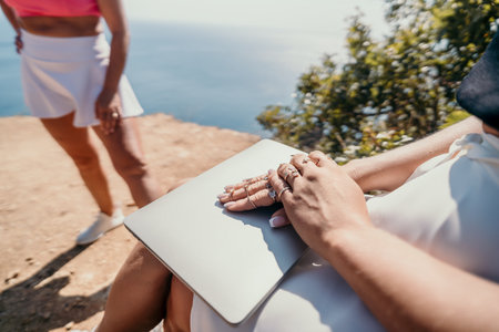 Close-up of Female Hands with Rings Holding a Laptop on a Beachの写真素材