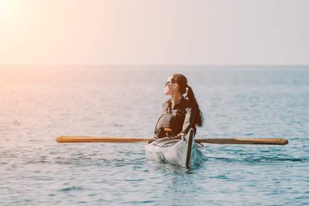Kayaking Woman Sea Sunset: Woman kayaking on the sea at sunset enjoying the calm waters.の写真素材