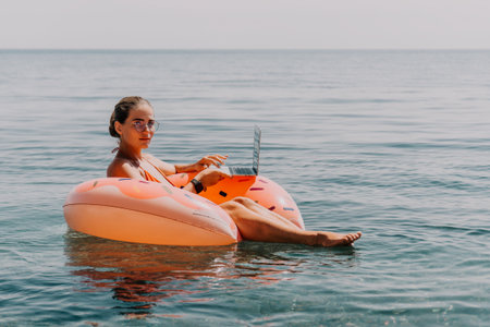 Woman Laptop Beach Floating on Inflatable Ringの写真素材