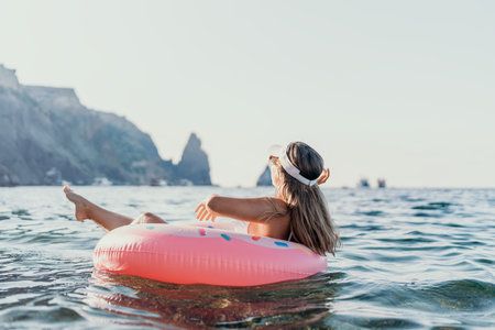 Woman floating sea, enjoying a relaxing summer vacation on a donut ring near majestic cliffs with...