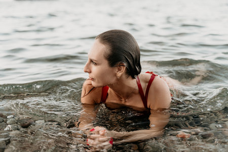 Woman, water, swimming. Relaxed young woman swimming in clear sea near pebbles.の写真素材