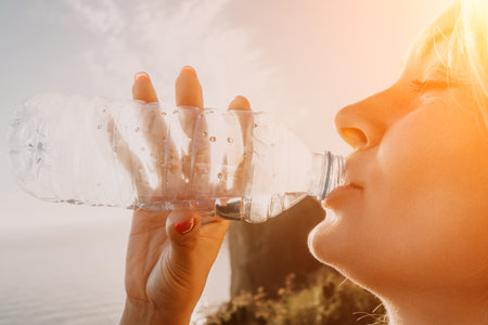 Woman Drinking Water from a Plastic Bottle in Natureの写真素材
