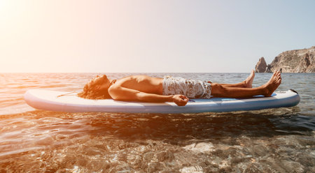 Man Paddleboard Relaxing Ocean - Man lying on a paddleboard in the ocean, relaxing in the sun.の写真素材
