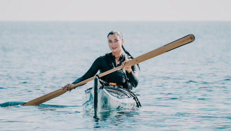 Woman Kayaking Ocean Paddle Smiling woman kayaking on calm ocean water, holding a paddle.の写真素材