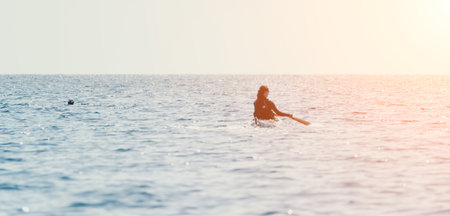 Woman Paddleboarding Ocean Sunsetの写真素材