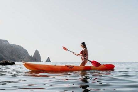 Woman Kayaking Ocean Coastline Seascape - A woman paddles a kayak in the ocean with a scenic coastline in the background.の写真素材