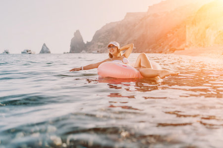 Woman, floating, sea. Relaxed woman floats on an inflatable donut ring in the open sea near cliffs...