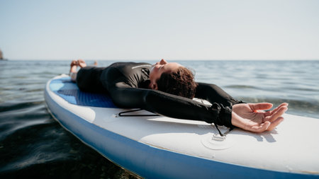 Yoga Paddleboard Water Sport Woman Practices Yoga on Paddleboard in the Oceanの写真素材