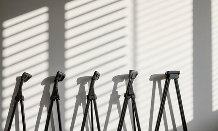 Rolling Stand Shadows - repeating striped shadow pattern from window blinds cast over a row of folded light stands againstの素材