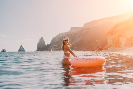 Woman, beach, ocean. Young woman in white bikini stands with donut float enjoying a sunny summer vacation.の写真素材