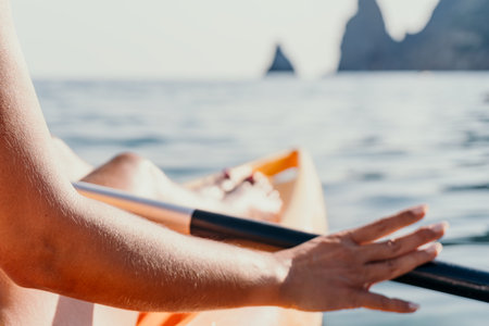 Kayaking Ocean Hand Paddle Close-up of a hand paddling a kayak in the ocean with rocky cliffs in the background.の写真素材