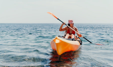 Kayaking Woman Ocean Water Sports - A woman in a pink hat kayaks on the ocean during a sunny day, enjoying water sports.の写真素材