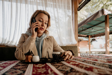Woman on a Phone Call in a Cozy Cafeの写真素材