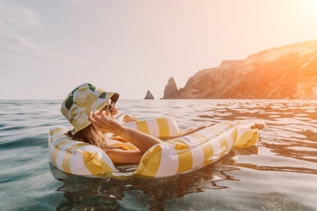 Woman, Inflatable Raft, Beach: Floating on an inflatable raft in the ocean with a view of mountains.の写真素材