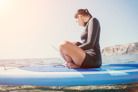 Woman Laptop Paddleboard Ocean Work Remotely Beachの写真素材