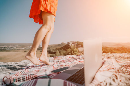 Relaxation on the Clifftop: Womans Legs with Laptop and Plaid Blanketの写真素材