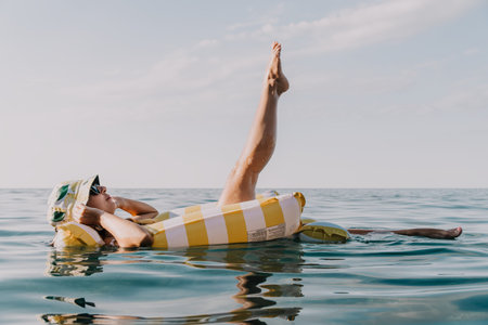 Woman, Inflatable, Sea: Relaxing on a yellow and white striped inflatable in the ocean.