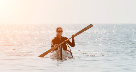 Kayaking Paddle Ocean Woman - A woman paddles a kayak in the ocean at sunset.