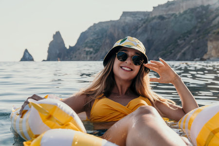 Woman Beach Float Summer - Smiling woman relaxing on a yellow float in the sea on a sunny day.