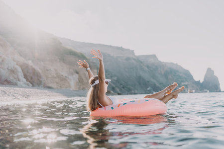 Woman, donut float, beach. Happy woman relaxing on donut float enjoying summer vacation at seaの写真素材