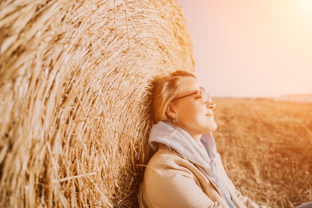 Woman Relaxing Against Hay Bale in Golden Field