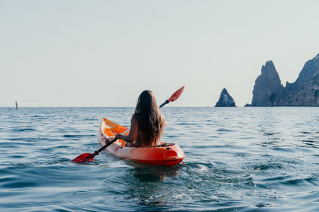 Kayaking Woman Sea - Woman kayaking in the sea with rocky mountains in the background.の写真素材