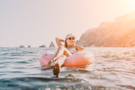 Woman, ocean, summer vacation. Young woman relaxing on a pink inflatable ring in the clear sea under...