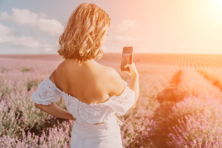 Lavender woman smartphone taking a photo in a blooming purple field during sunset golden hour capturing natureの写真素材