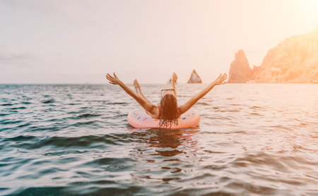 Woman, floating, sea. A woman relaxes floating on an inflatable ring in the open sea enjoying a...