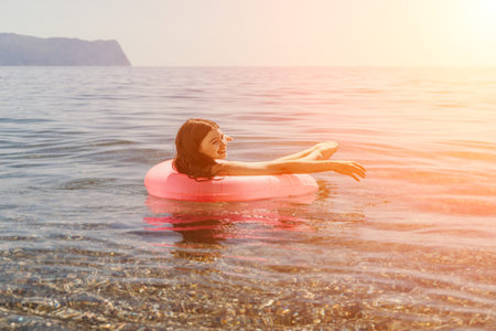 Woman floating sea happy young girl relaxing on a pink inflatable ring in the calm ocean water...