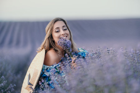 Woman lavender field smiling while smelling a bouquet in a blooming purple meadow during sunset with copy spaceの写真素材