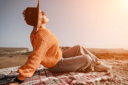 Woman in a Brown Hat and Orange Sweater Relaxing on a Blanket