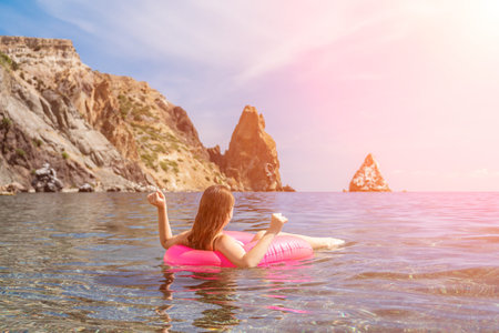 Swimming woman ocean relaxed woman floats on a pink inflatable ring in clear blue sea water near...