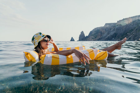 Woman, Inflatable, Sea - Woman relaxing on yellow inflatable ring in the sea near a rocky coastline.
