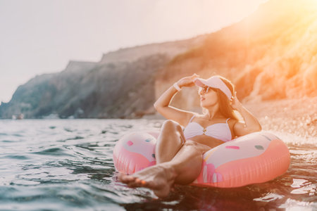 Woman, floating, sea. Beautiful woman floating on an inflatable donut in the sea near a rocky coast,...