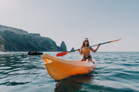 Kayaking Woman Sea - Woman paddling kayak in ocean near cliffs on sunny day.の写真素材