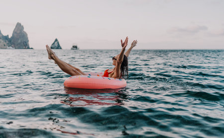 Woman, sea, inflatable. Relaxing on donut ring with arms up in ocean, enjoying summer.