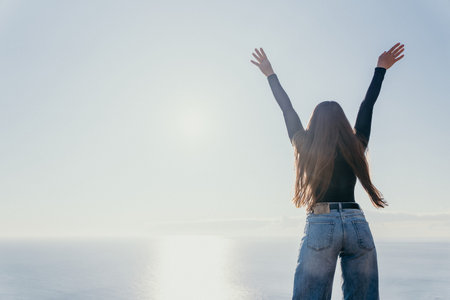 Freedom woman ocean stands with her arms raised facing the vast sea to celebrate success and peace...