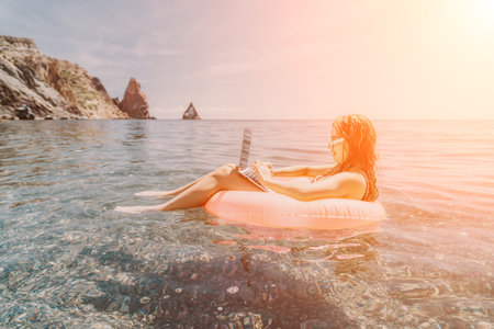 Laptop beach woman young professional works remotely while floating on an inflatable ring in the sea...