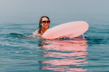 Woman swimming float, joyful summer vacation holiday at the misty sea with pink inflatable tube