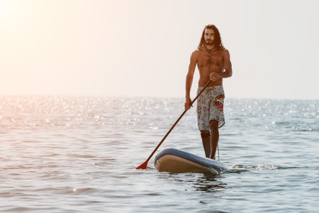 Man Paddleboard Ocean - Man on Paddleboard Enjoying the Ocean at Sunset.の写真素材