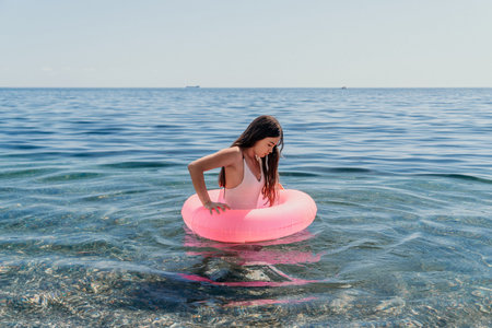 Woman swimming inflatable ring enjoying summer leisure in clear blue sea water copy space