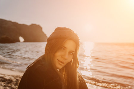Woman, Beanie, Sunset, Attractive woman in beanie looks back on the beach during a beautiful orange...